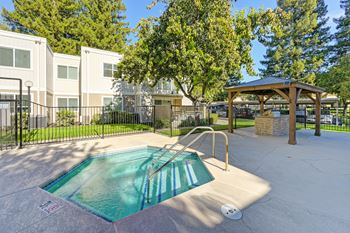 A small pool in a fenced in area with a pavilion in the background.